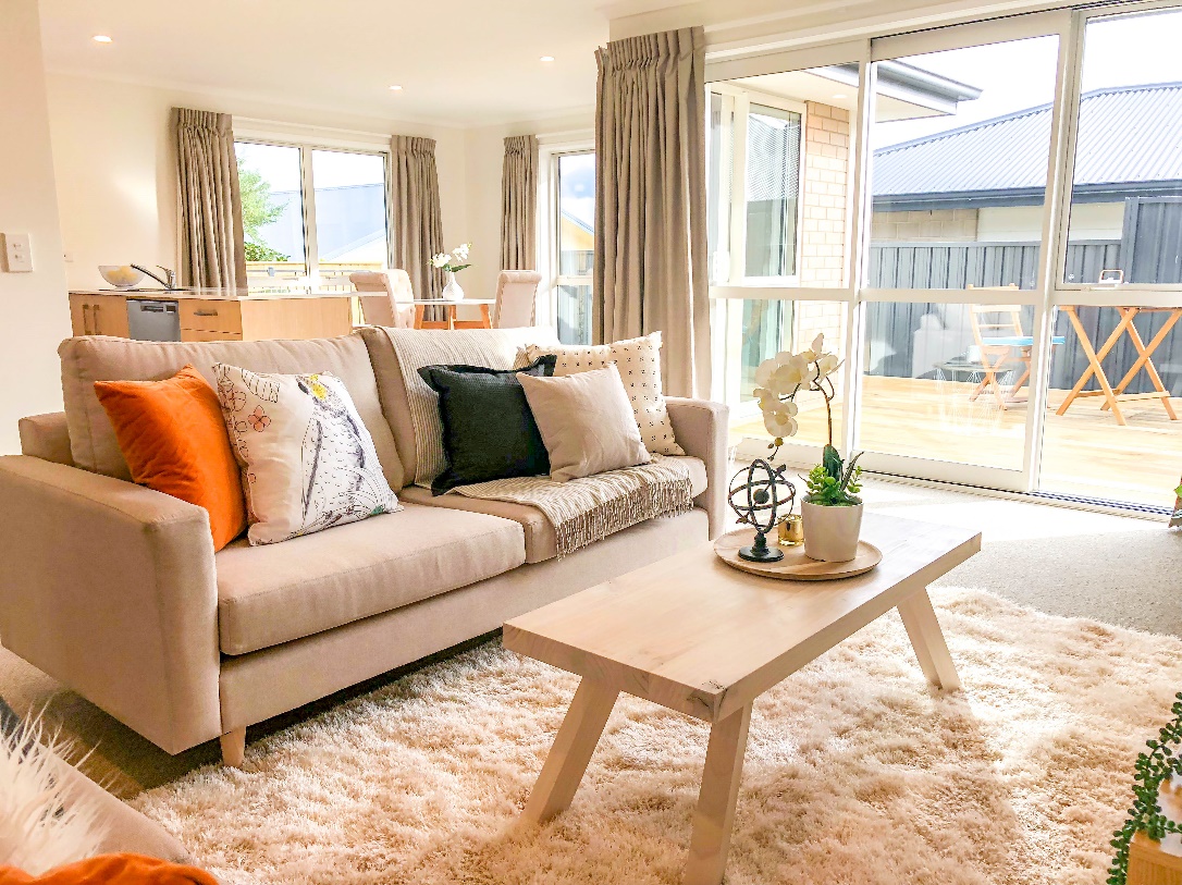 A home staged open plan space - the living area is in the foreground with a kitchen and dining area in the background